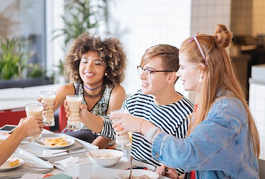 Teenager stoßen am-Esstisch an