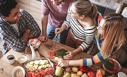 Junge Erwachsene kochen gemeinsam in einer Küche. 