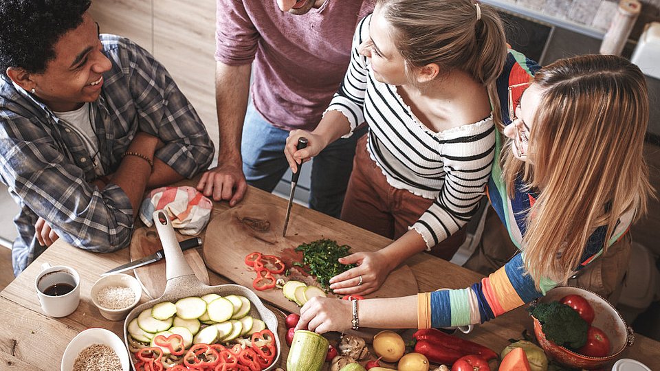 Junge Erwachsene kochen gemeinsam in einer Küche. 