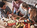Junge Erwachsene kochen gemeinsam in einer Küche. 