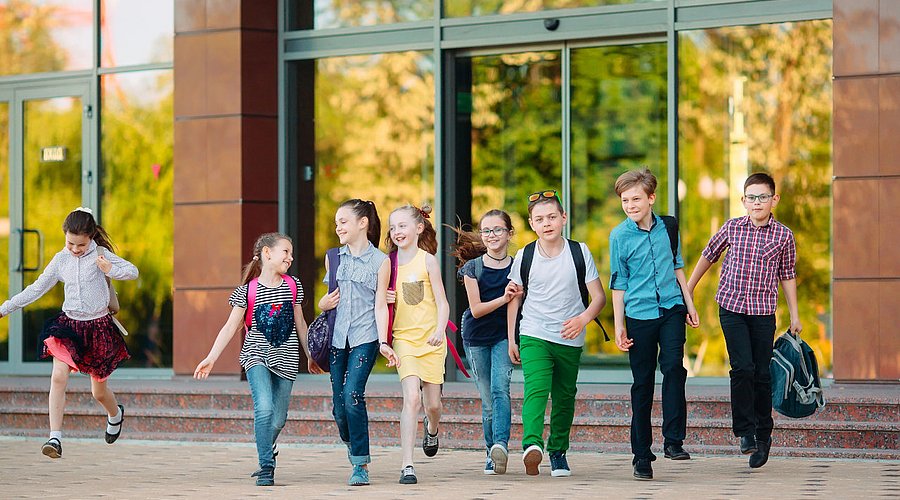 Fröhliche Gruppe von Kindern kommt aus der Schule.