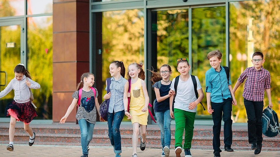 Fröhliche Gruppe von Kindern kommt aus der Schule.