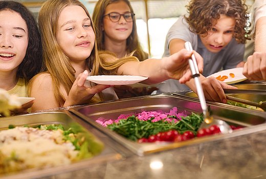 Kinder bedienen sich selbst am Buffet in der Schulmensa