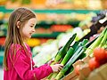 Ein Schulkind kauft Gemüse in einem Supermarkt.