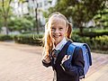 Britisches Grundschulmädchen in Schuluniform und Tornister.