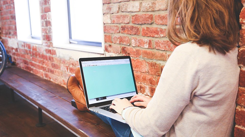 Schülerin arbeitet mit hochgelegten Füßen am Laptop