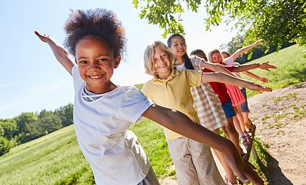 Schulkinder balancieren auf einem Spielgerät.   
