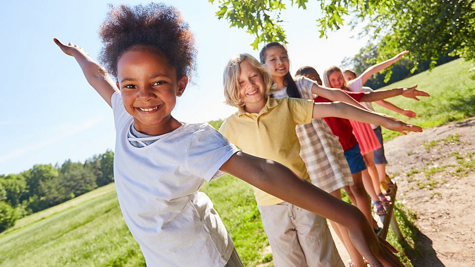 Schulkinder balancieren auf einem Spielgerät.   
