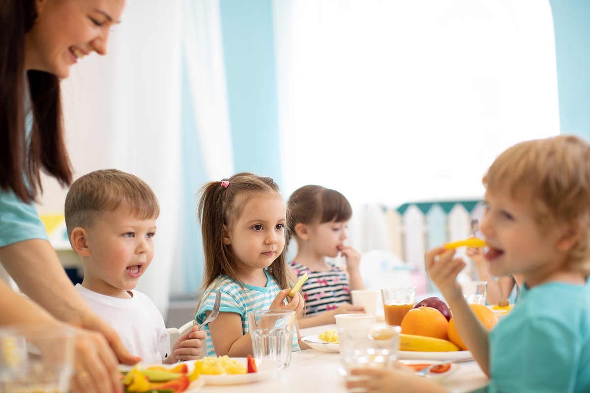 Kinder sitzen an einem Tisch und essen