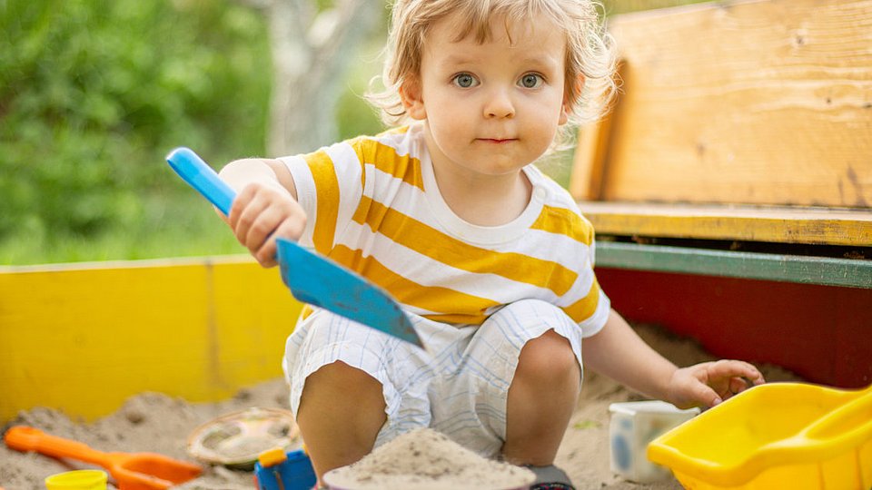 Ein Kita-Kind spielt im Sandkasten.