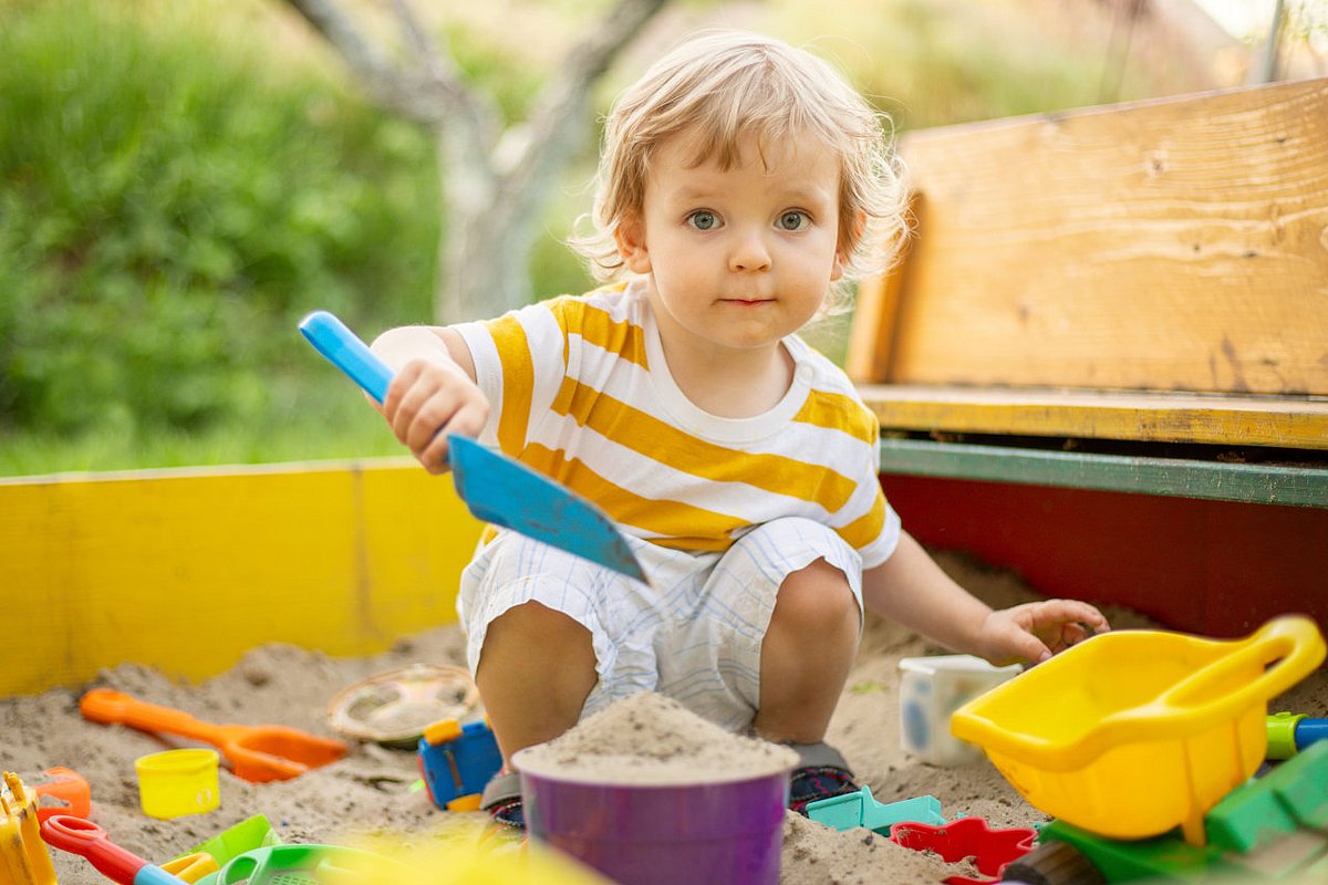 Ein Kita-Kind spielt im Sandkasten.