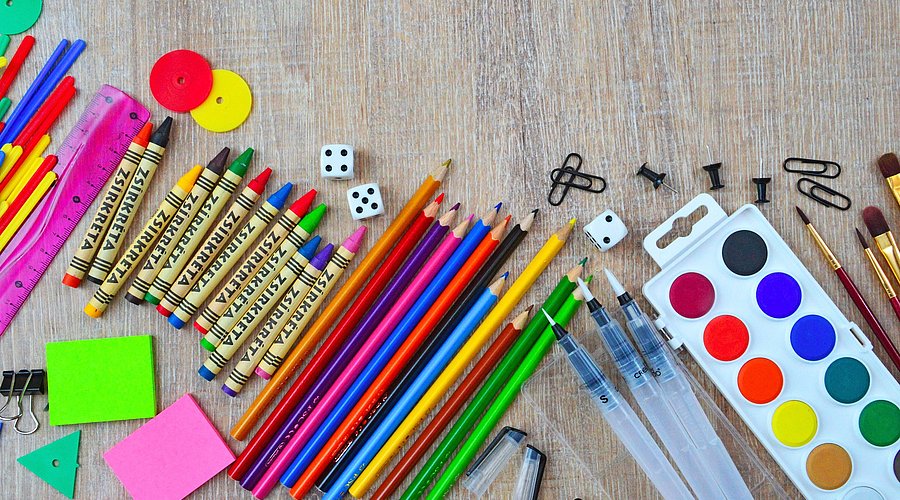 Auf einem Tisch liegen Malutensilien für Schulkinder. 