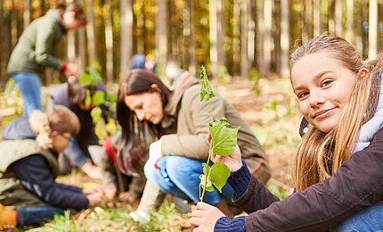Mädchen pflanzt einen Baum-Setzling als Klimawandelbaum. 