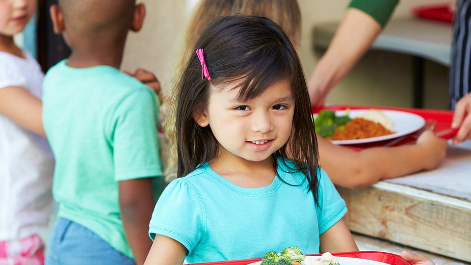 Schulkinder holen sich ein gesundes Mittagessen in der Schule. 