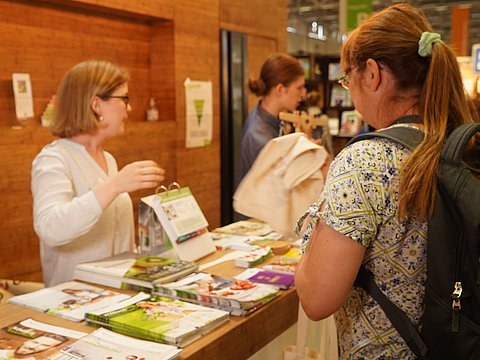 Besucherin betrachtet Medienauslage am IN FORM Messestand.