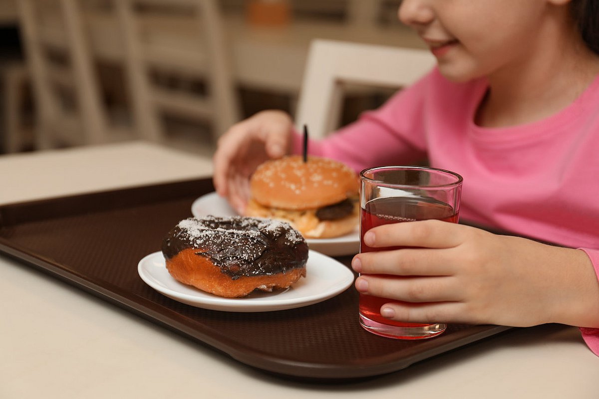 Schulmädchen isst Burger und Donut in der Schule.