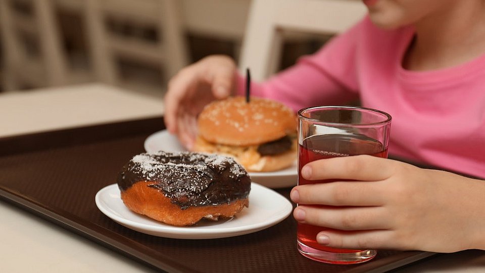 Schulmädchen isst Burger und Donut in der Schule.
