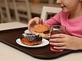 Schulmädchen isst Burger und Donut in der Schule.