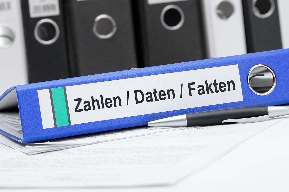 Blauer Ordner zu Zahlen, Daten, Fakten liegt auf dem Tisch