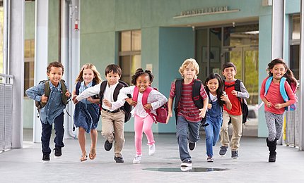 Grundschulkinder laufen über den Flur einer Schule.