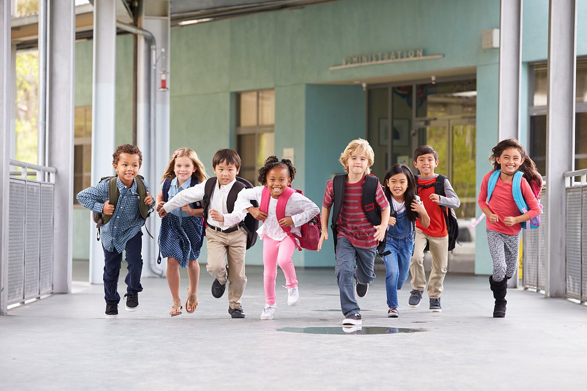 Grundschulkinder laufen über den Flur einer Schule.