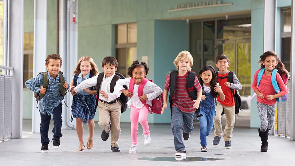 Grundschulkinder laufen über den Flur einer Schule.