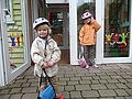 Zwei Kinder mit Fahrradhelm stehen an einer geöffneten Kita-Tür.