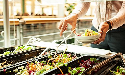 Eine Studentin bedient sich am Salatbuffet. 