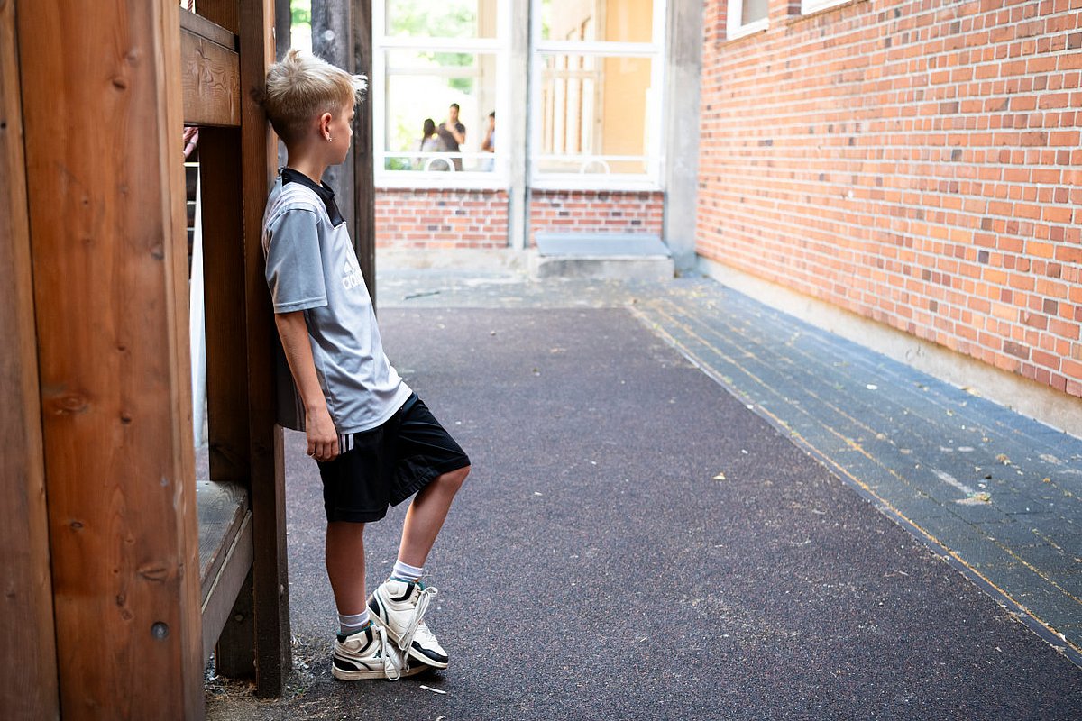 Ein Junge steht auf dem Spielplatz der Grundschule.  