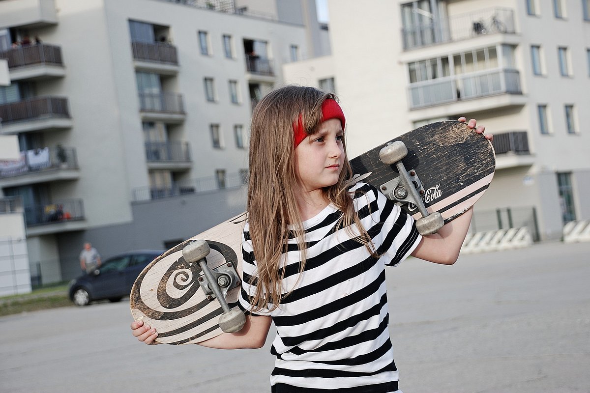 Jugendliches Mädchen mit Skateboard auf der Straße