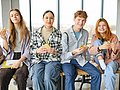 Teenager sitzen in der Schulmensa auf einem Tisch und snacken.
