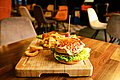 Auf einem Holzbrettchen liegt ein Burger mit Pommes frites.