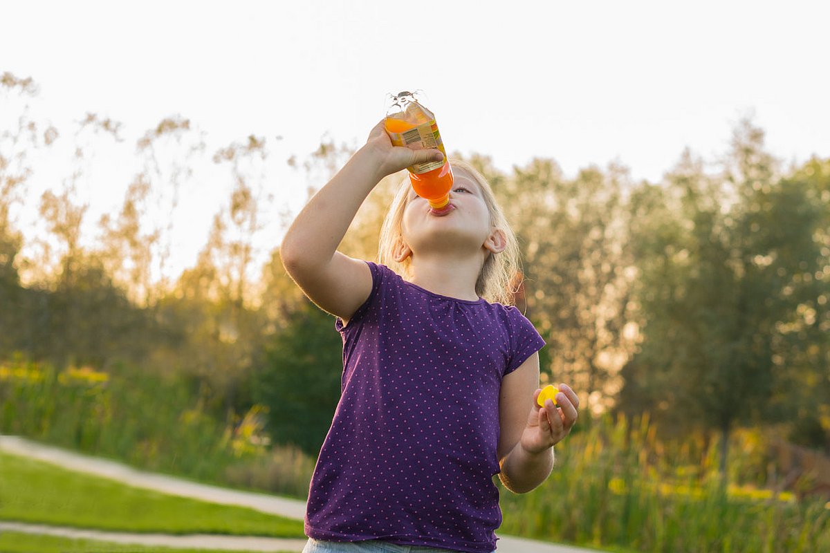 Schulkind trinkt Limonade aus einer Plastikflasche. 
