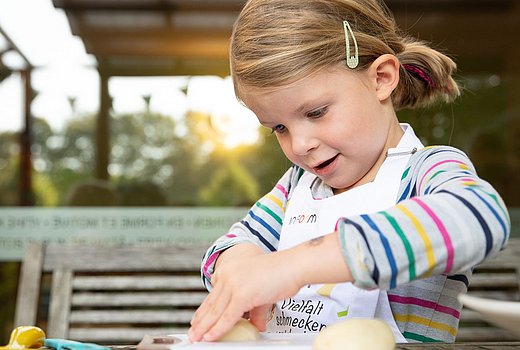 kleines Mädchen schneidet Kartoffel