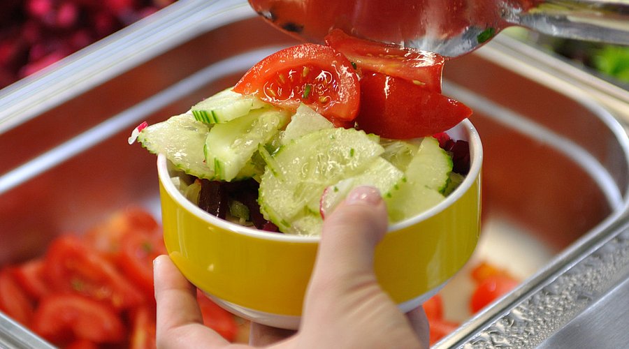 Eine Schülerin bedient sich in der Schulmensa an einer Salatbar.