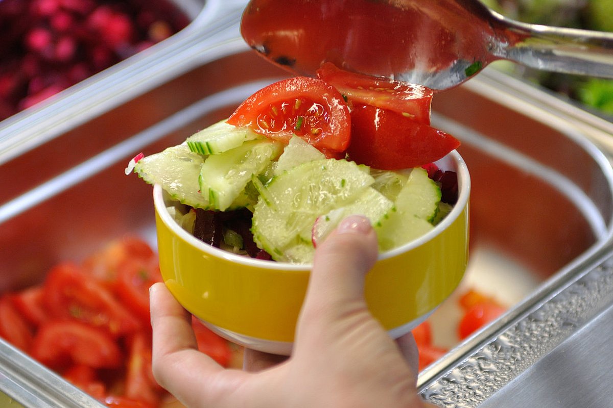 Eine Schülerin bedient sich in der Schulmensa an einer Salatbar.