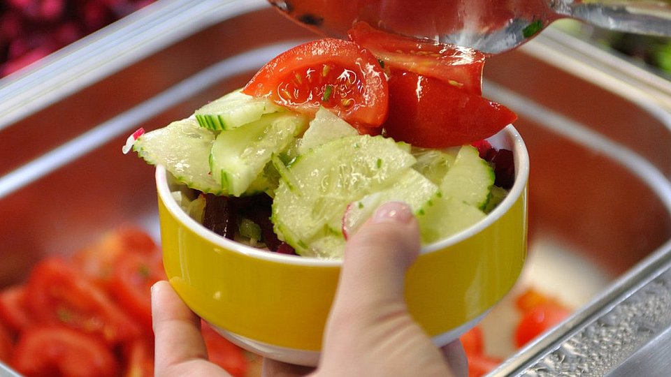 Eine Schülerin bedient sich in der Schulmensa an einer Salatbar.