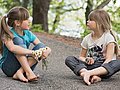 Zwei junge Mädchen sitzen auf der Straße und unterhalten sich.