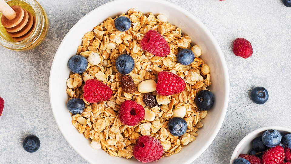 Schüssel mit Müsli und Beeren auf hellem Hintergrund