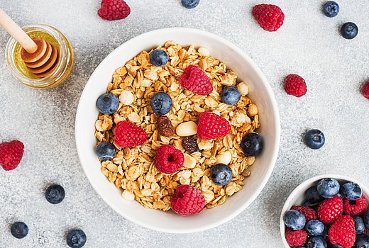 Schüssel mit Müsli und Beeren auf hellem Hintergrund