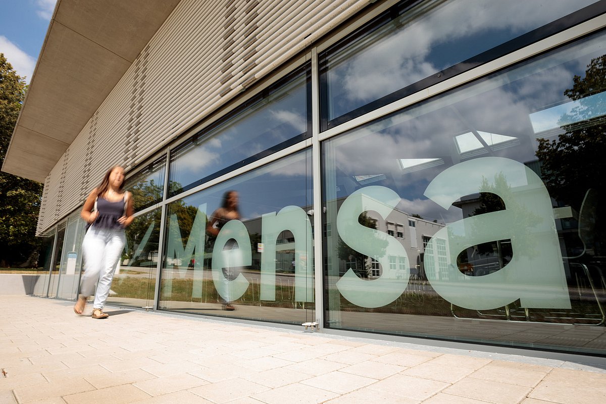 Studentin geht an einer Mensa entlang.