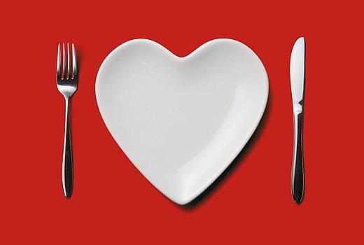 Herzf&ouml;rmiger Teller mit Besteck auf rotem Grund