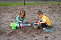 Zwei Kinder spielen im Sandkasten.