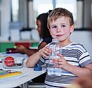 Schulkind mit Trinkflasche im Klassenraum
