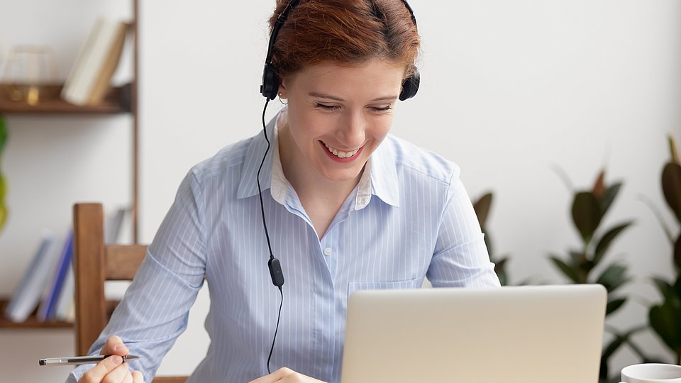 Eine Frau sitzt am Arbeitsplatz und betreibt Selbststudium 