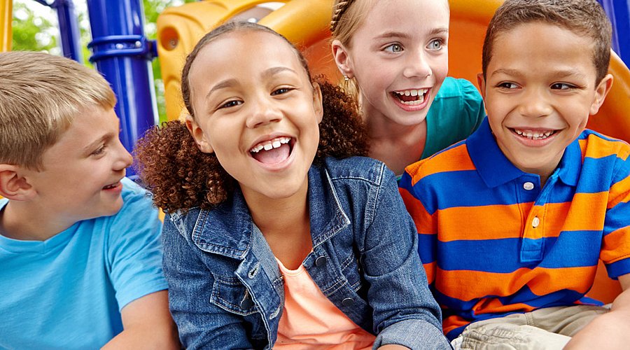 Lachende Kinder spielen im Freien auf dem Spielplatz. 
