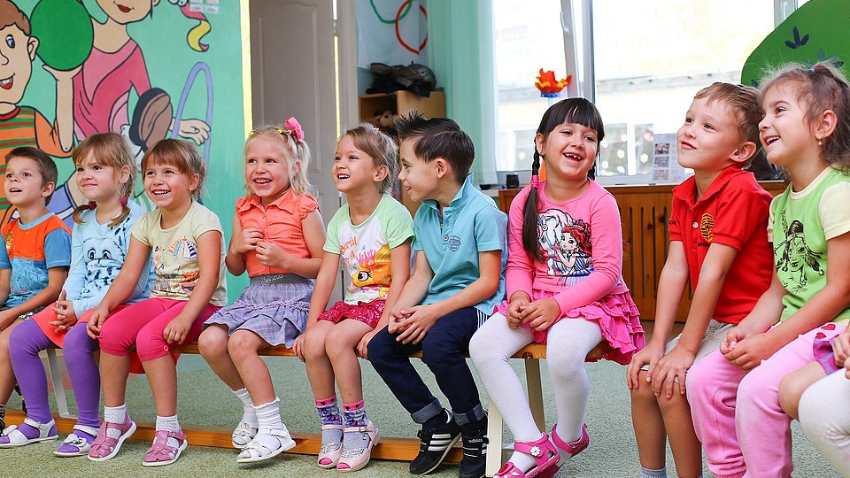 Kita-Kinder sitzen auf einer Bank