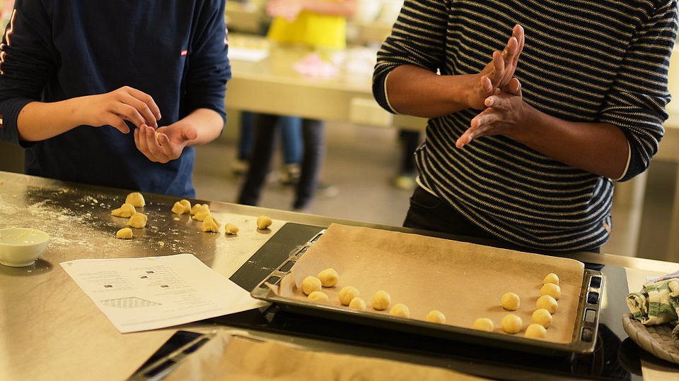 Schüler backen in einer Schulküche. 