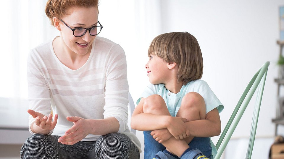 Mitarbeiterin in der Ganztagsbetreuung in Grundschule spricht mit Schulkind. 