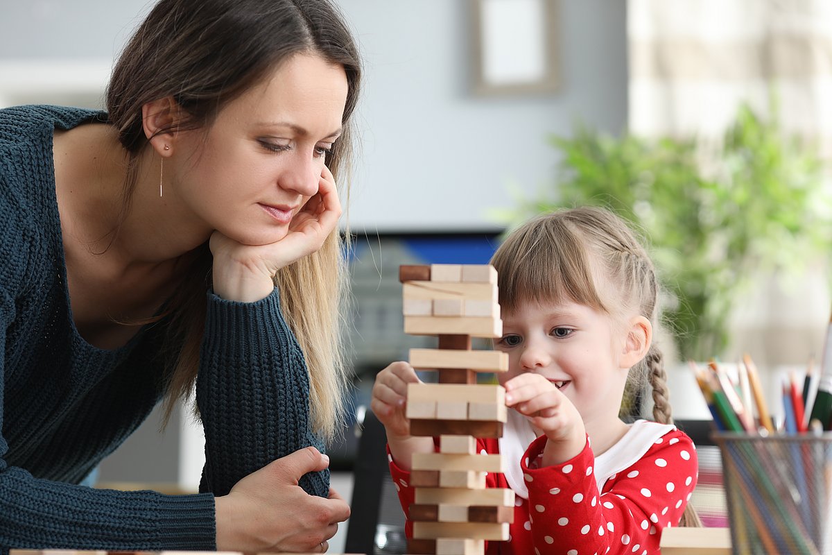 Kind und Frau bauen einen Holzspiel-Turm.